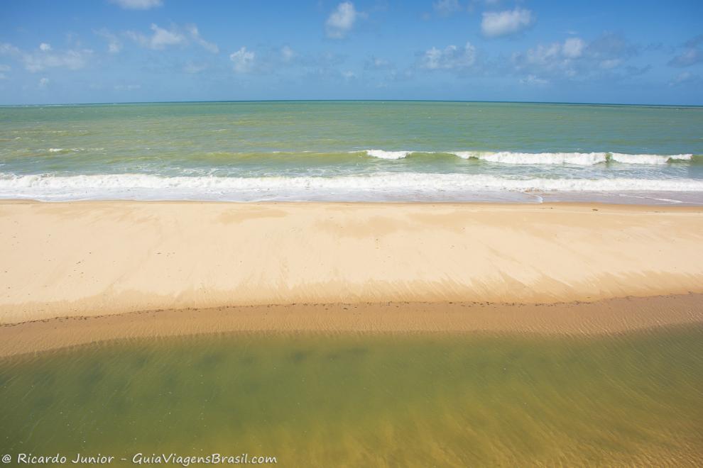 Imagem das águas cristalinas da piscina natural da Praia Japara Grande e do mar.